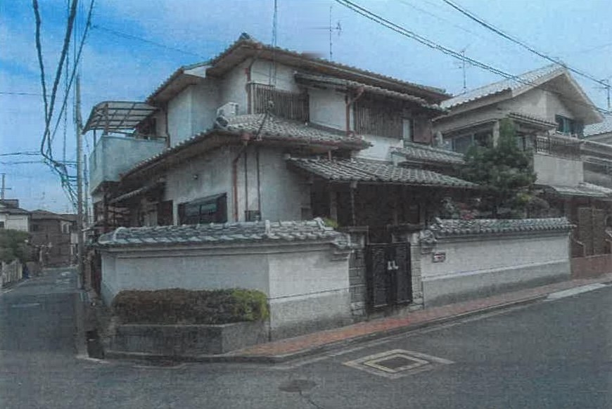 Two-storey tiled-roof house behind its garden wall in Habikino. Photograph from the court survey file; annotation marks removed.