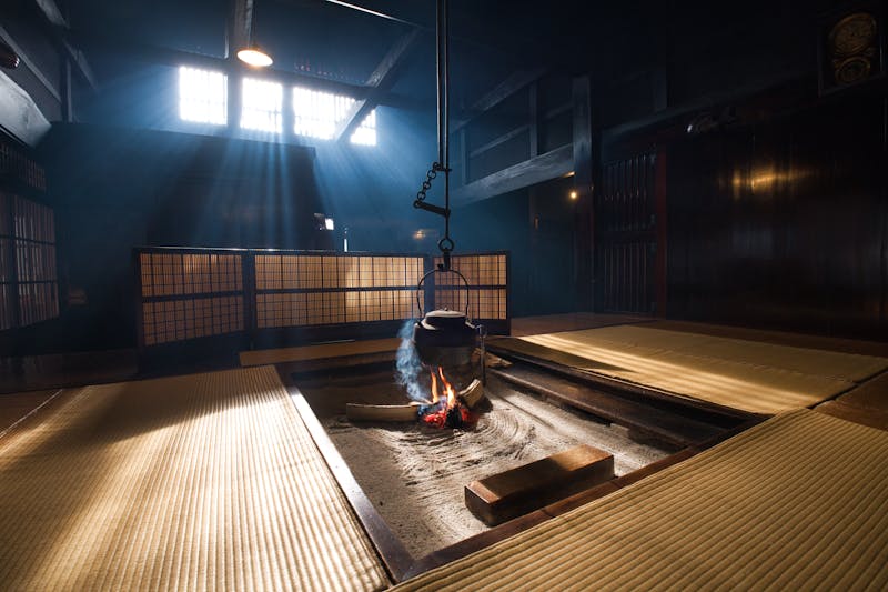 Traditional Japanese tatami room with irori hearth, sunlight through shoji screens
